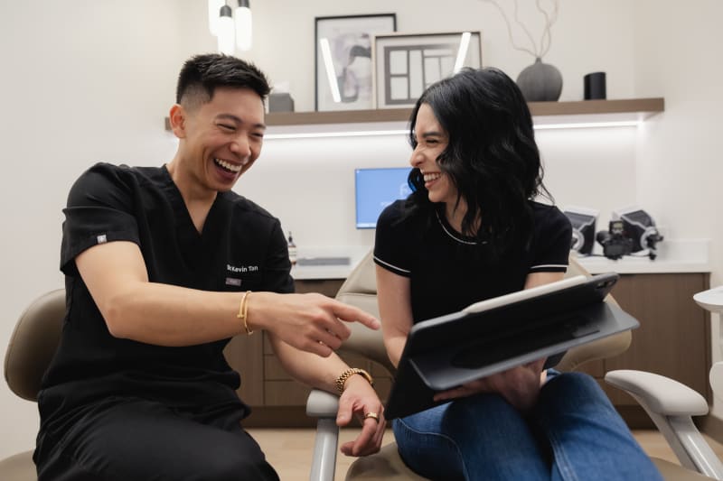 Dentist and patient discussing treatment plan together, reviewing information on tablet