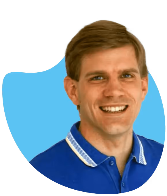 Lächelnder Mann mit kurzem braunem Haar und blauem Polohemd vor blauem Hintergrund.