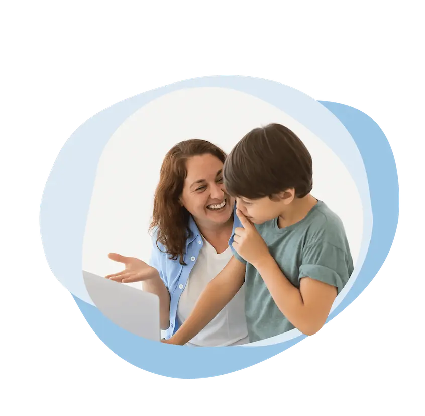 Frau lächelt und zeigt auf einen Laptop, während ein Junge neben ihr scherzhaft die Nase berührt.