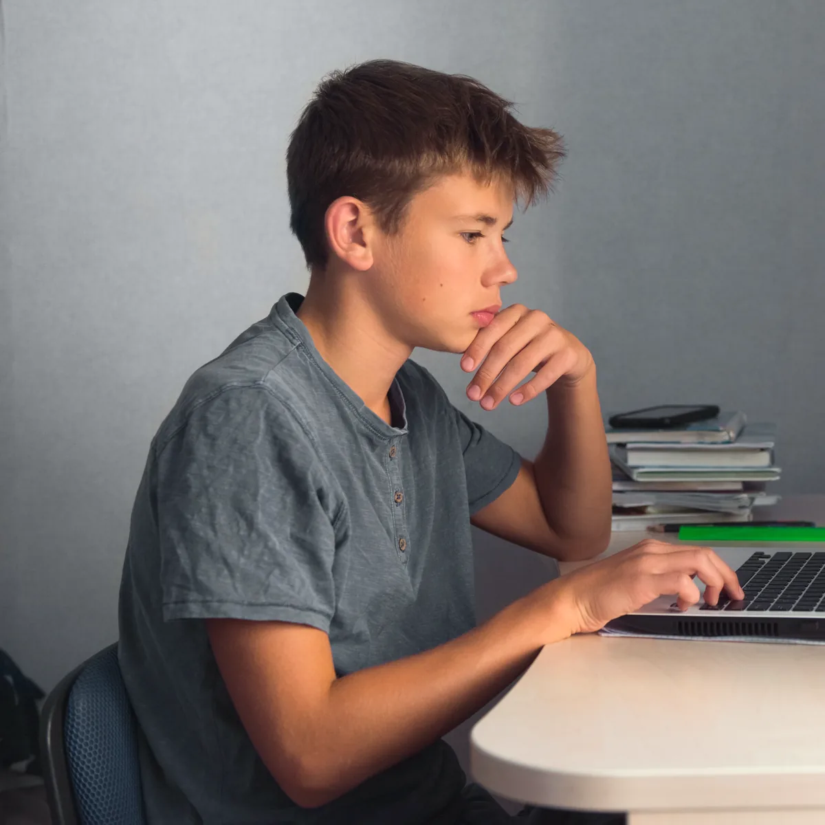 Junge sitzt zu Hause am Schreibtisch und lächelt in die Kamera