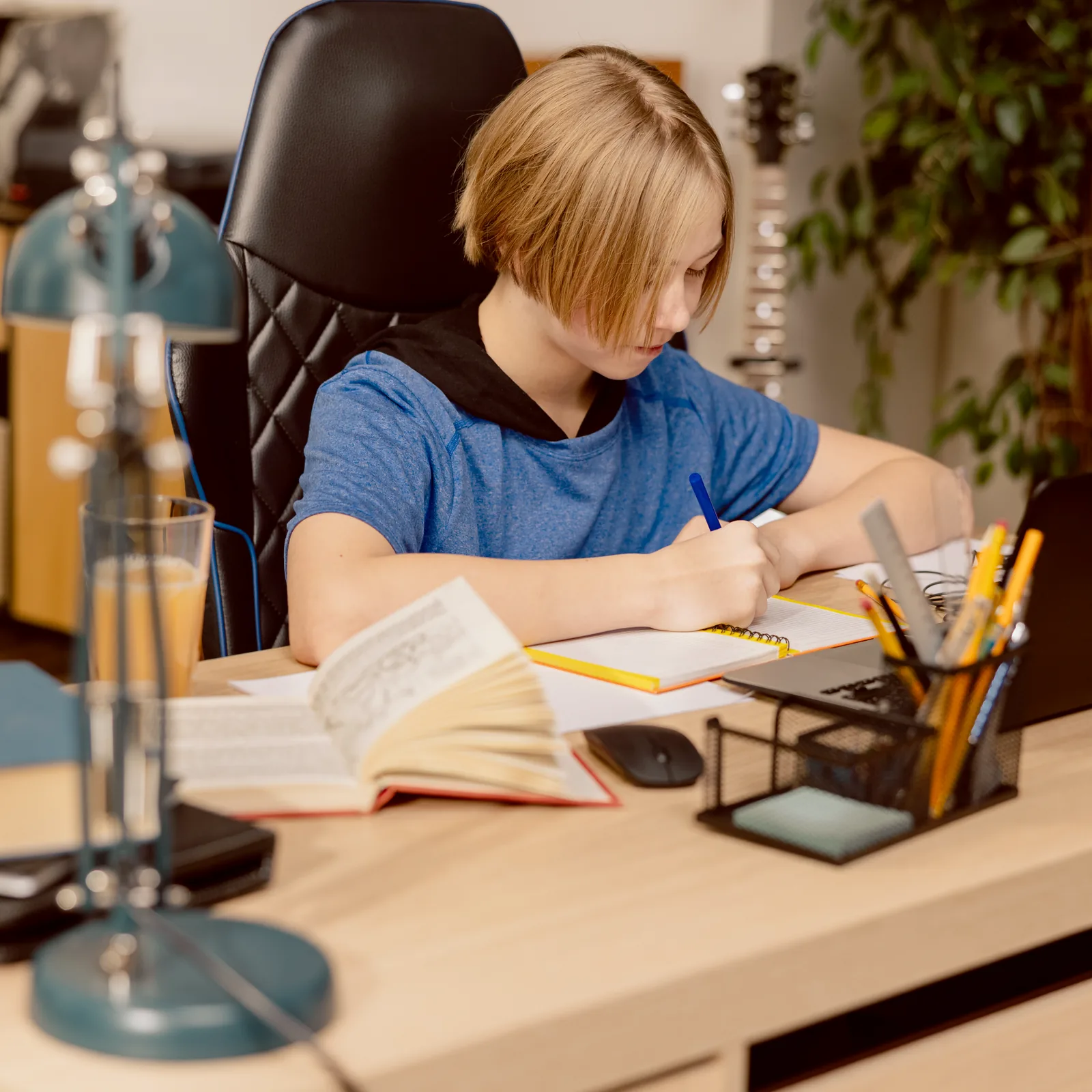 Junge im blauen Shirt lernt zu Hause am Laptop