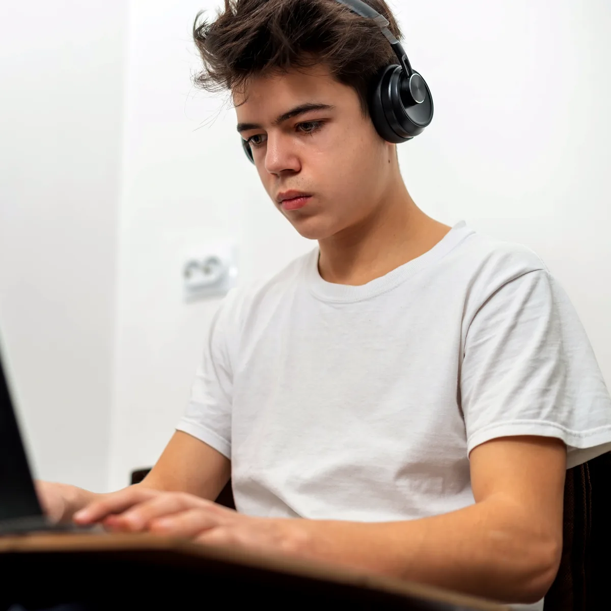 Junge mit Kopfhörern nimmt an einer Online-Session am Laptop teil