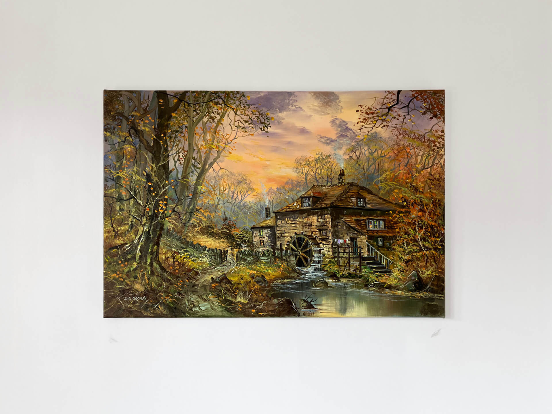 A picturesque mill surrounded by trees, with a stream flowing peacefully in the foreground.