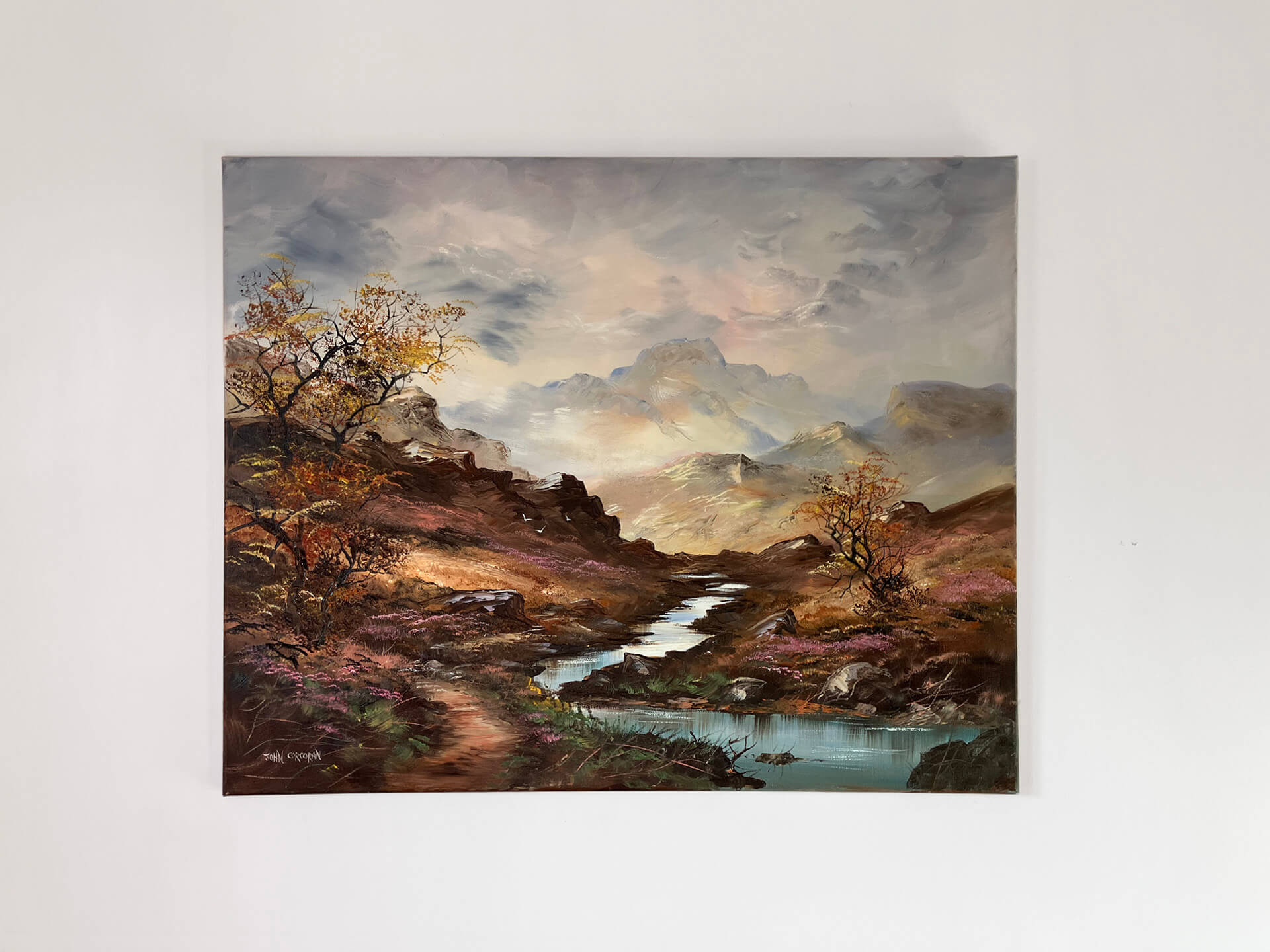 A picturesque river scene in the mountains, featuring vibrant trees and scattered rocks along the water's edge.