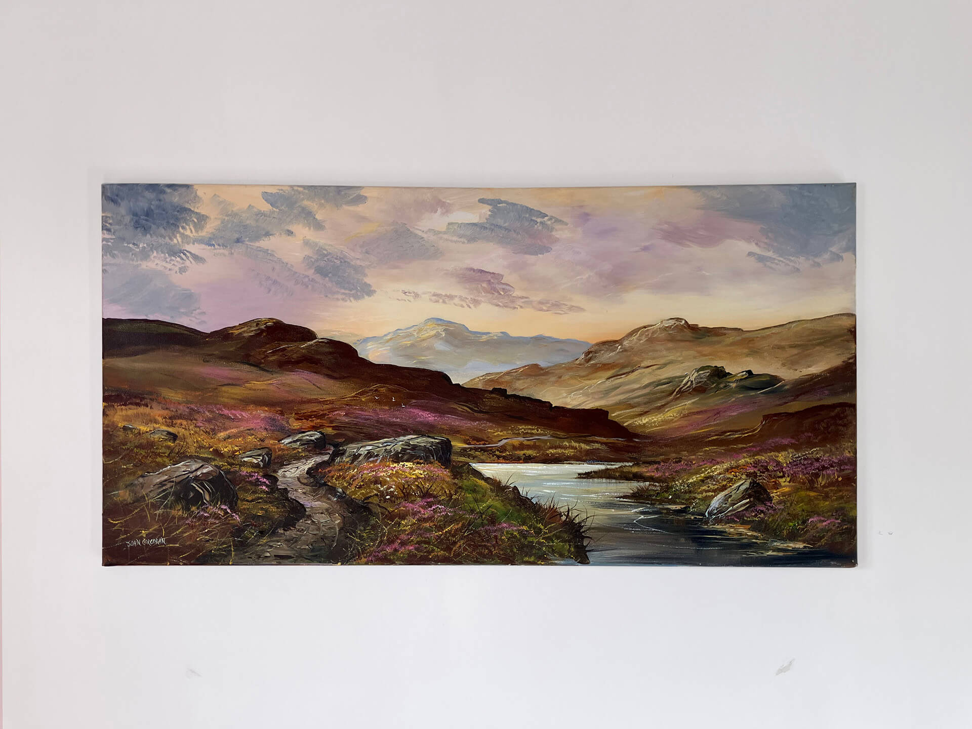 A picturesque view of a river flowing amidst the rugged, heather covered mountains of the Moorlands in a vibrant painting.