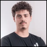 Portrait of a young man with curly hair and a mustache wearing a black shirt against a light background.
