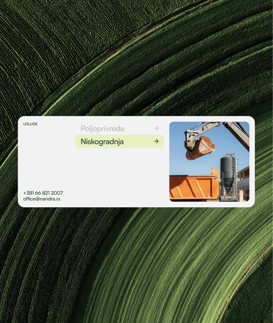 Construction site with excavator loading soil into an orange dump truck, next to a tall metal silo against a clear blue sky.