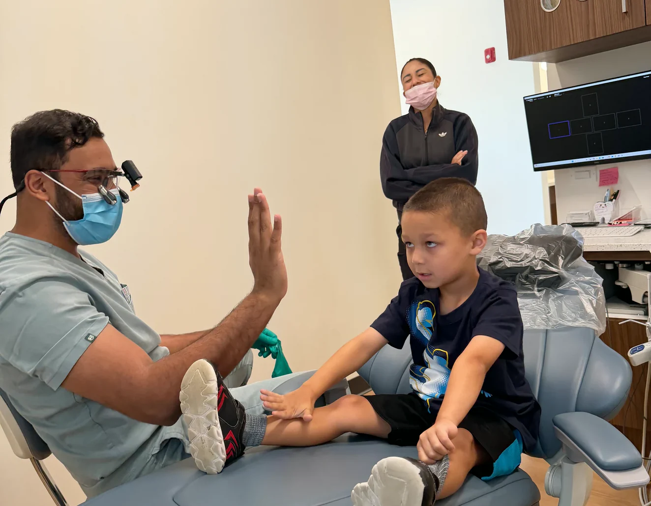 Dr. Sajan Parag high-fiving a young patient at Rinse Dental