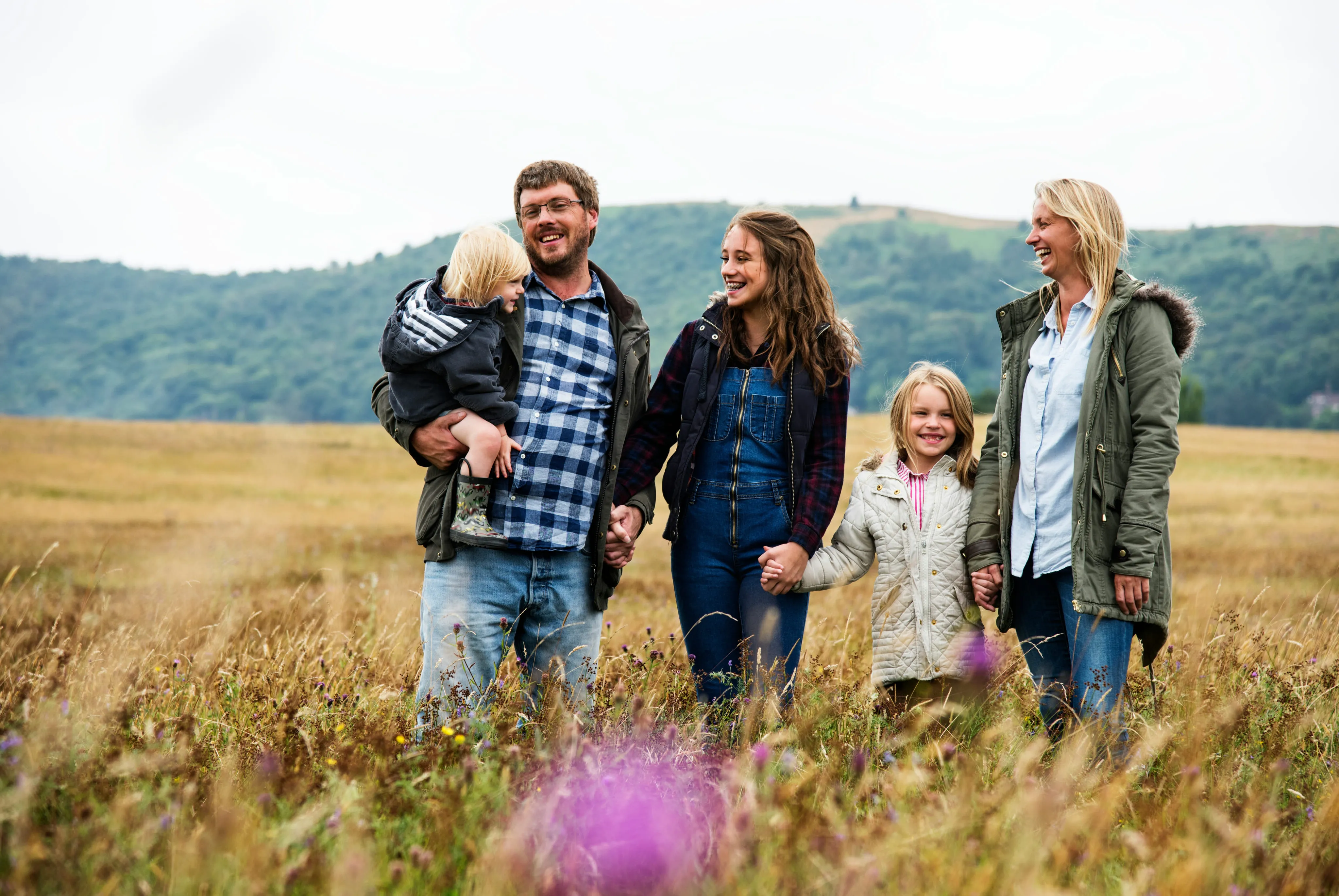Family walking together through an open Wyoming field with rolling hills in the background