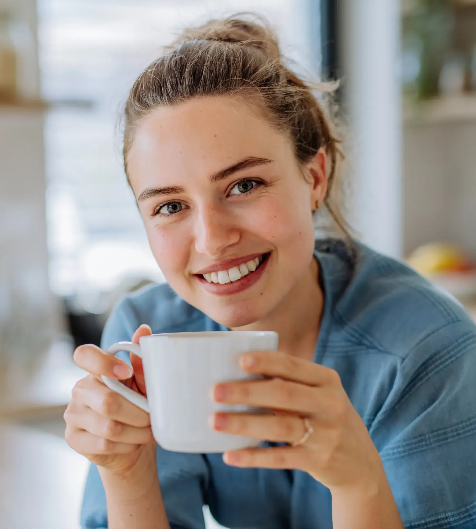 A smiling woman holding a cup of coffee.