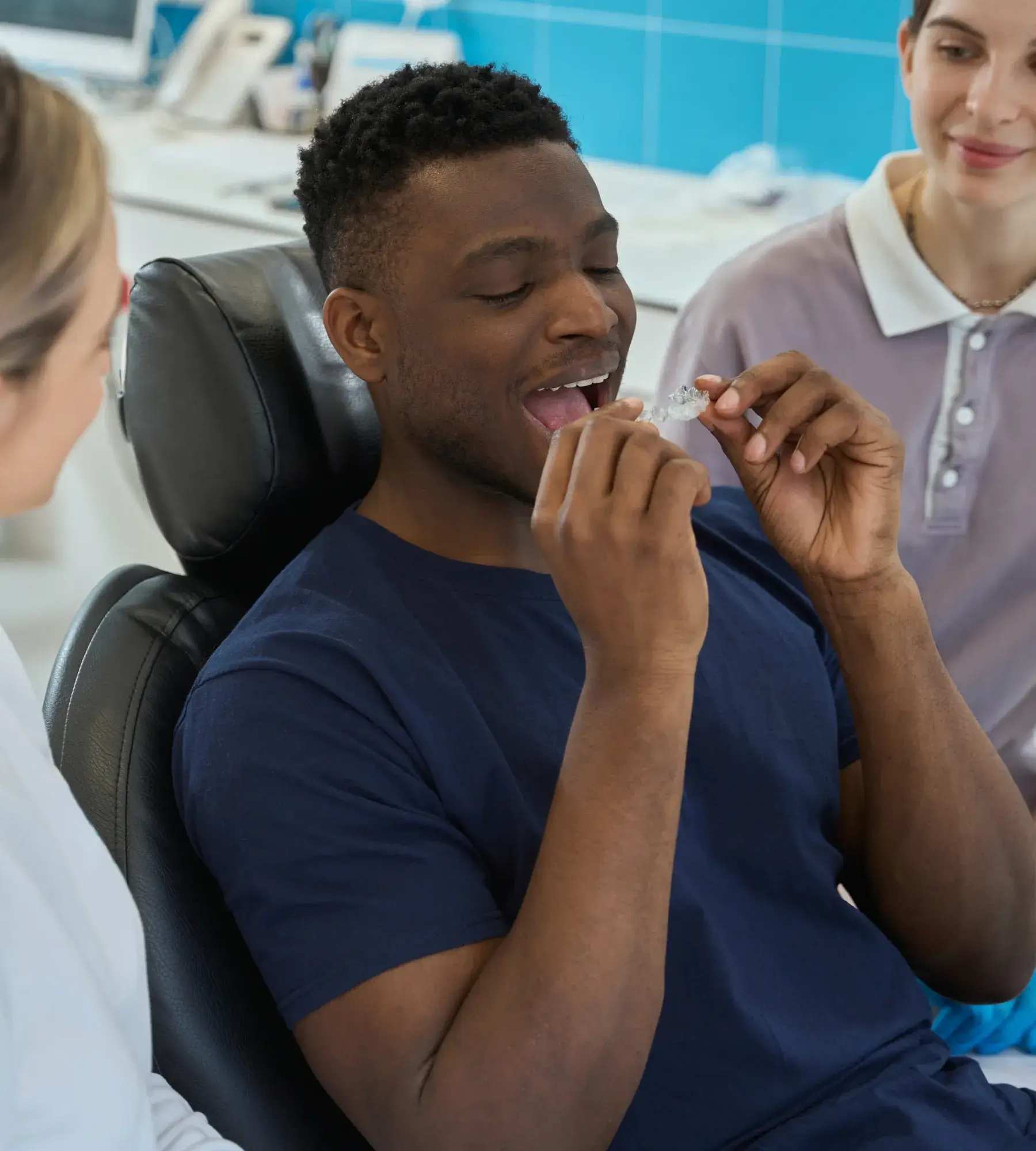 A man sitting in a dentist chair with a toothbrush in his mouth.