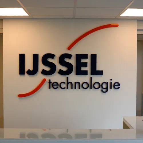 3D-wandbord met de tekst 'IJSSEL technologie' en twee gebogen oranje lijnen erboven en eronder.