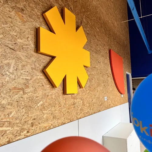 Binnenmuur met een grote gele stervormige decoratie en een kleinere rode geometrische vorm op een gestructureerde houten paneelachtergrond. goed voor akoestiek