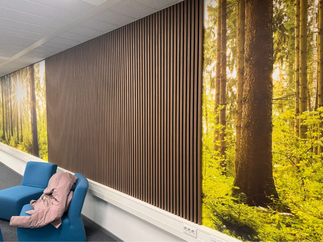 Blauwe loungestoel met daaroverheen een roze jas, tegenover een muur versierd met verticale houten latten en een levendige muurschildering van een bos.