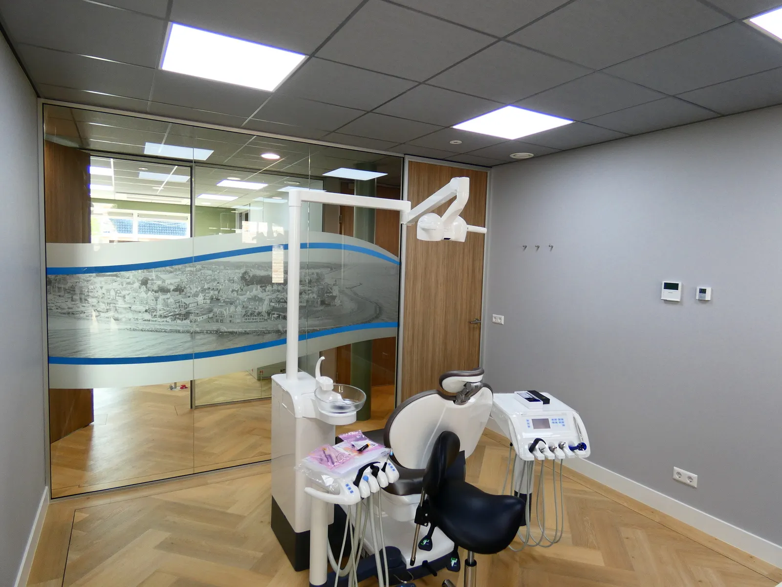 Moderne tandartsbehandelkamer met een tandartsstoel, instrumenten en een glazen wand met een stadsgezicht als decoratie.