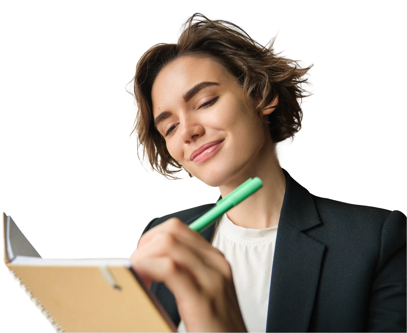 Smiling woman with short hair writing in a notebook with a green pen.