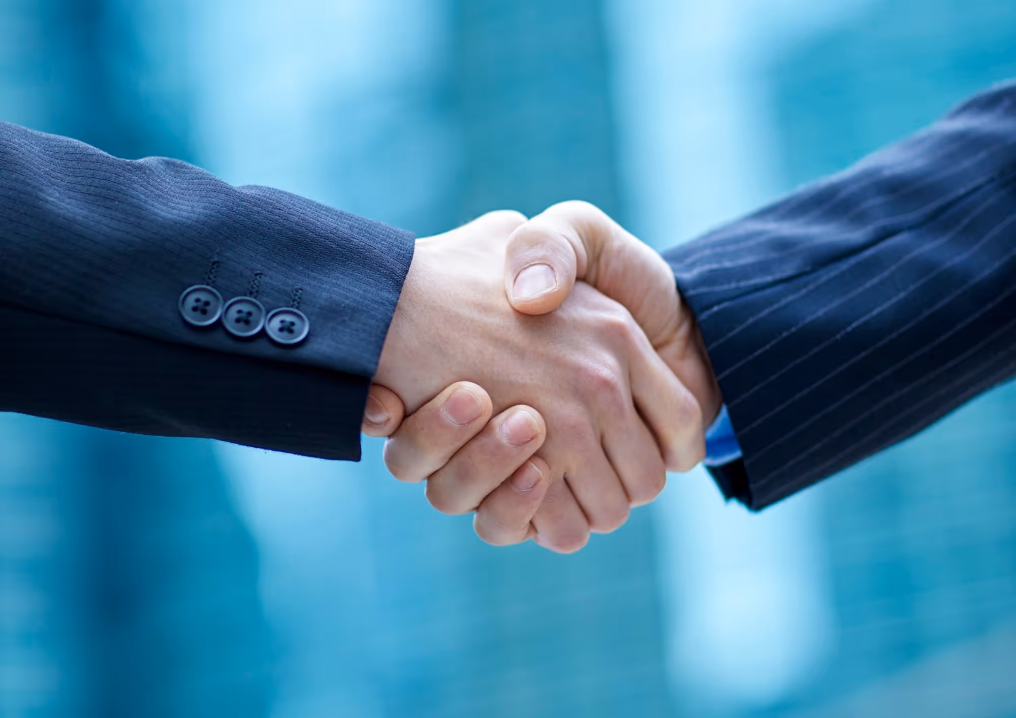 Close-up of two people in business suits shaking hands.