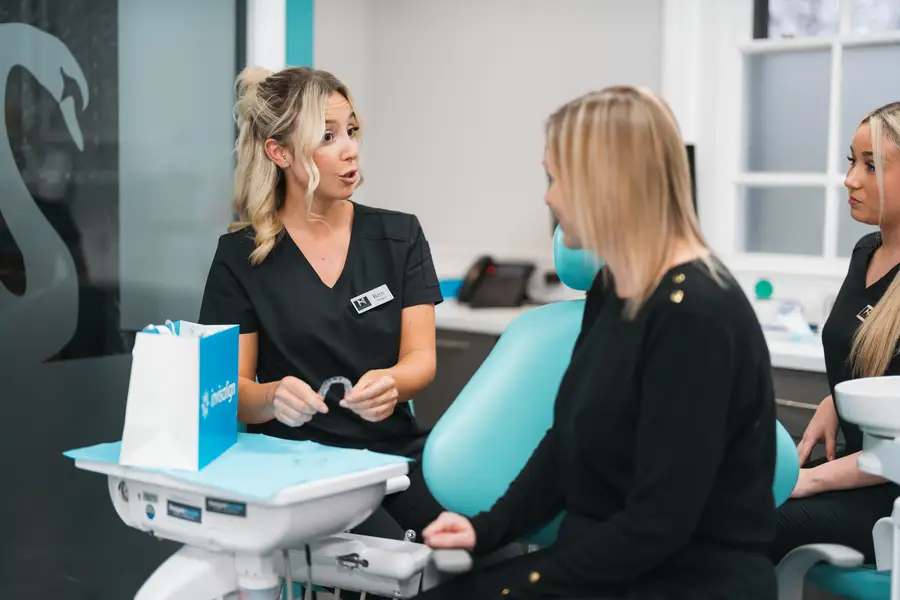 Dental professional explaining clear aligner treatment to a patient seated in a dental chair.