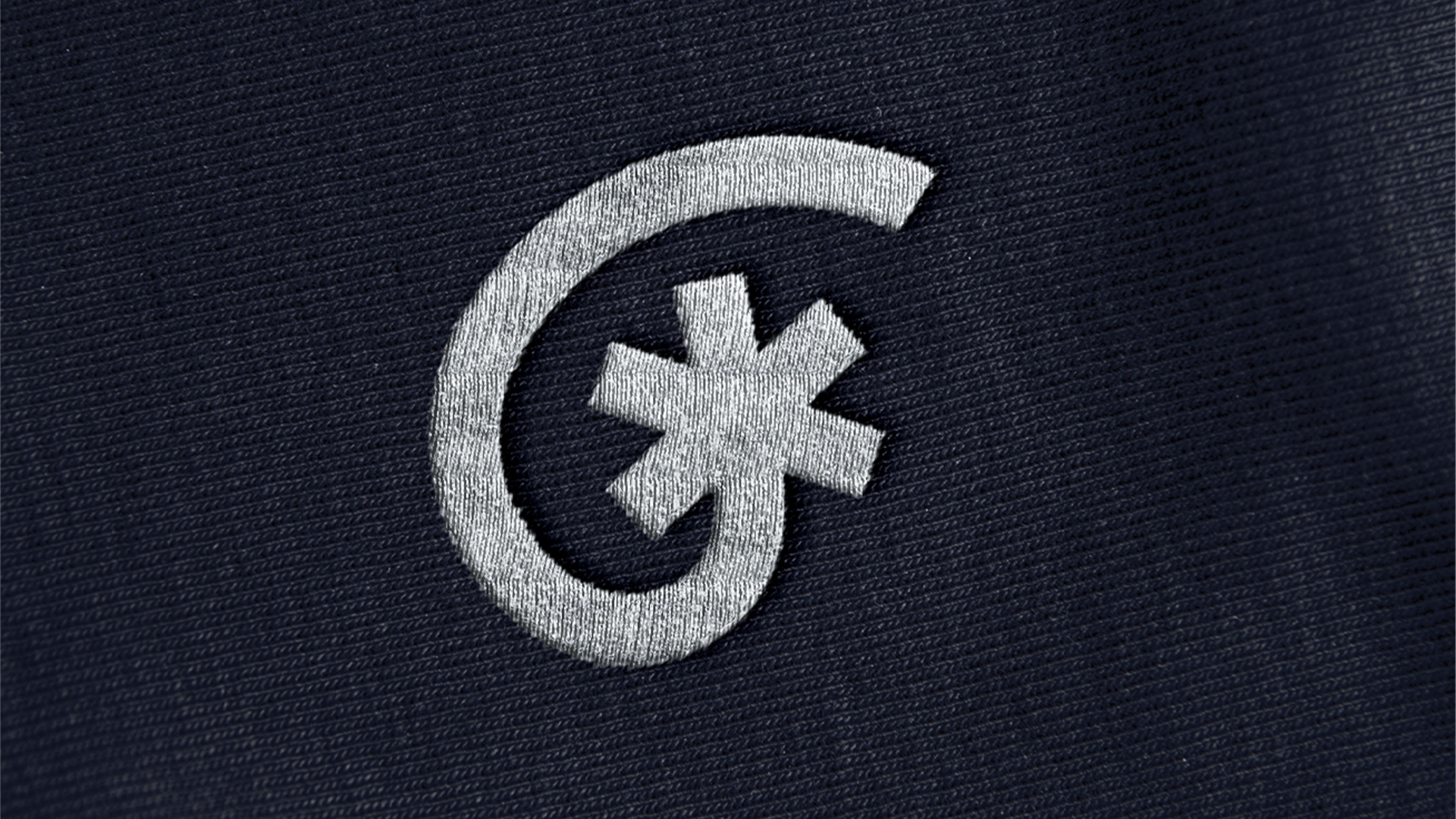 Symbole astérisque blanc brodé sur un tissu bleu foncé.