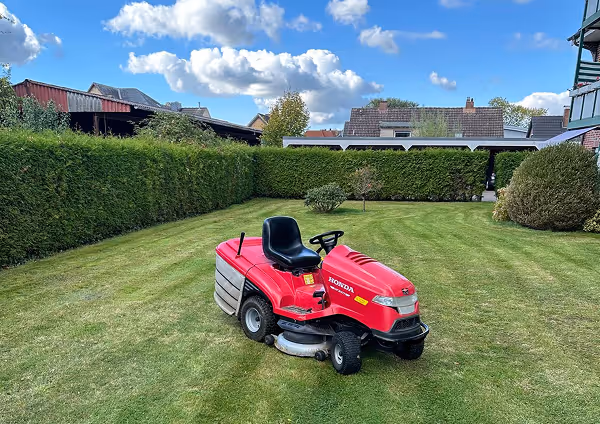 Roter Honda Rasenmäher auf einem gepflegten Rasen.
