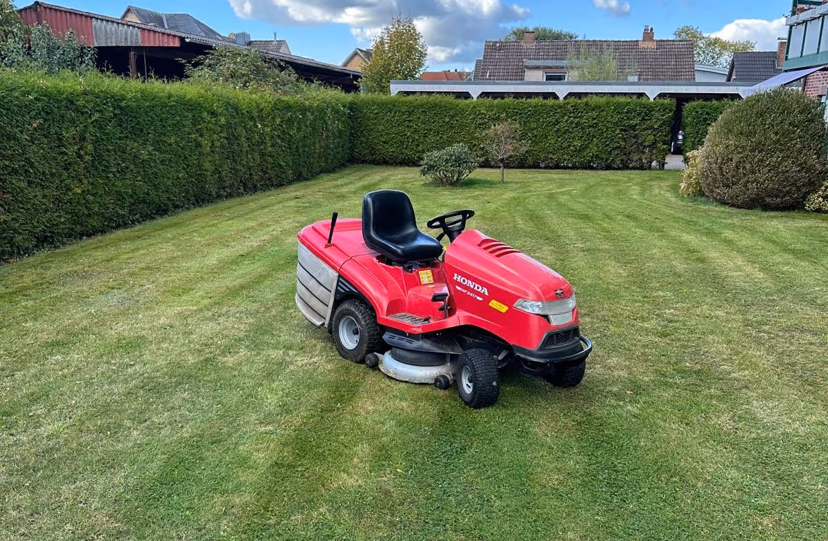 Roter Honda Rrasenmäher auf gepflegtem grünen Rasen.
