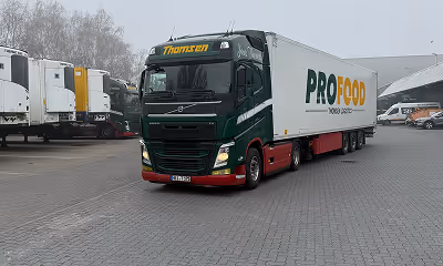 LKW mit der Aufschrift PROFOOD parkt auf gepflastertem Hof.