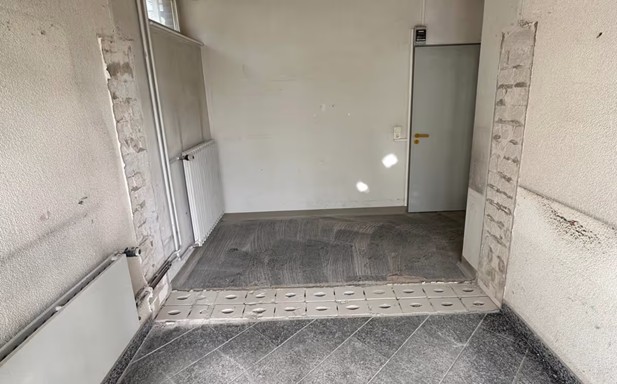 Sanierter und gefliester Durchgang mit weißer Tür.