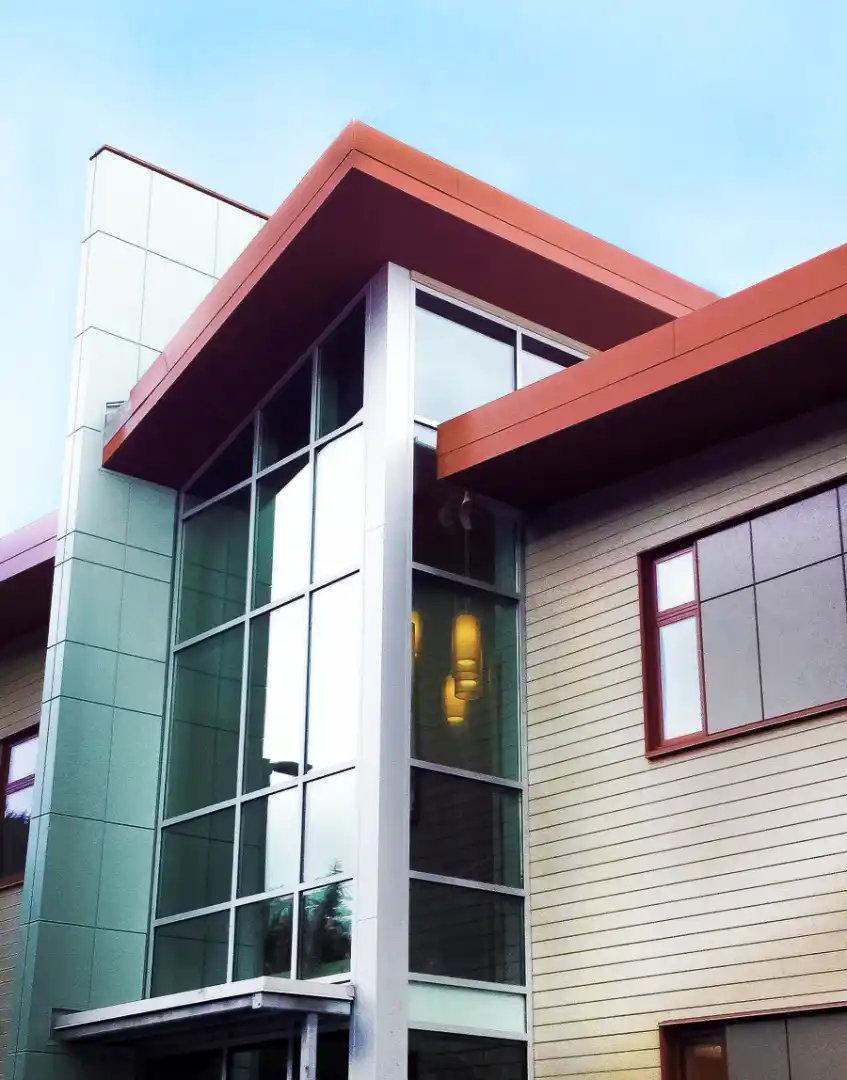 Tall glass stair tower with light blue metal panels and red roof fascia..