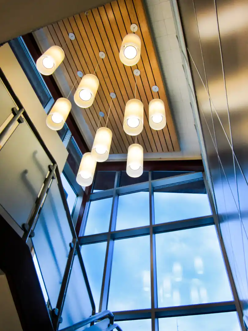 Stair tower looking up at cedar ceiling with multiple linear pendant lights.