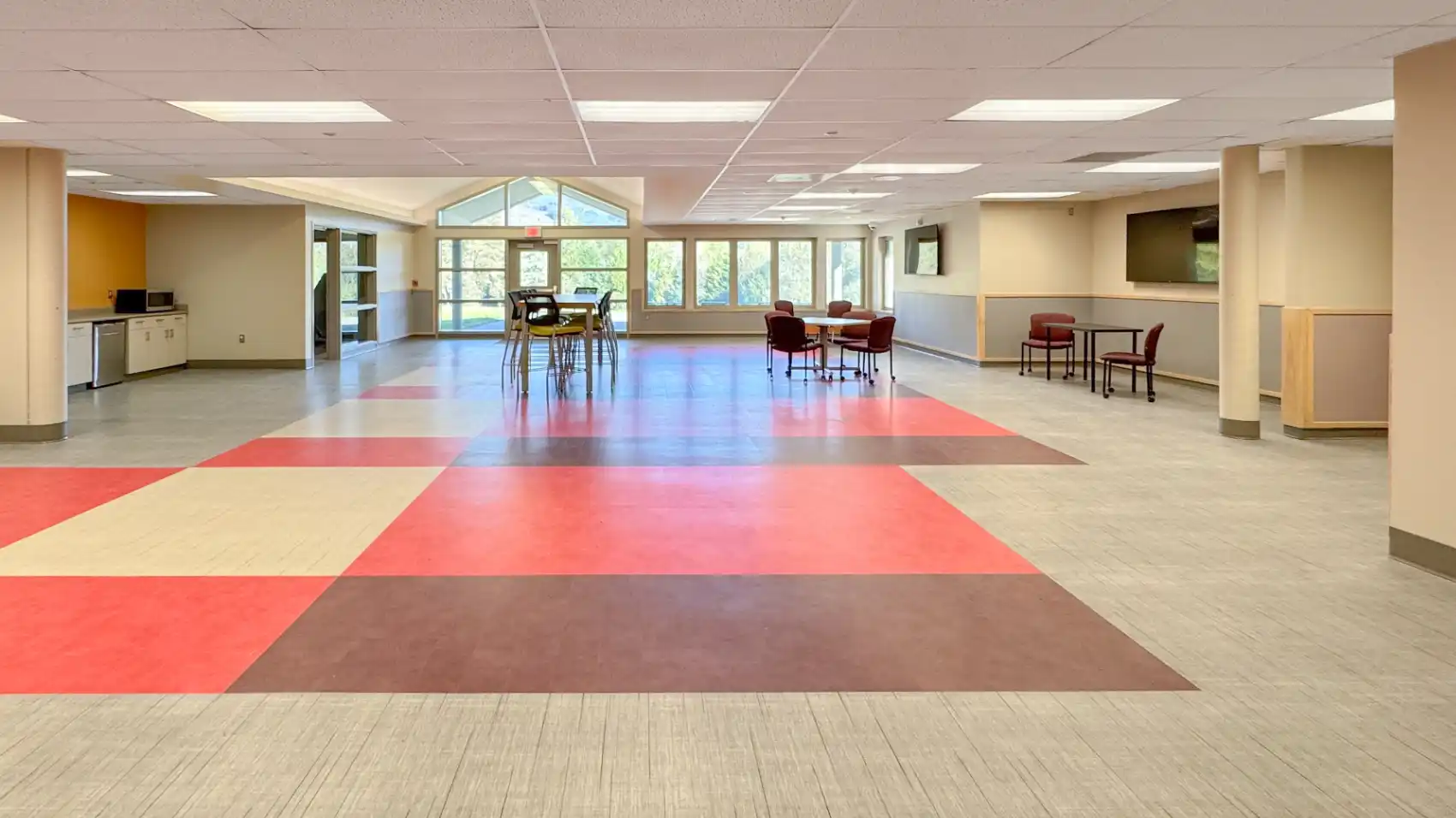 Open area with gabled ceiling, colorful patchwork flooring and lots of windows.