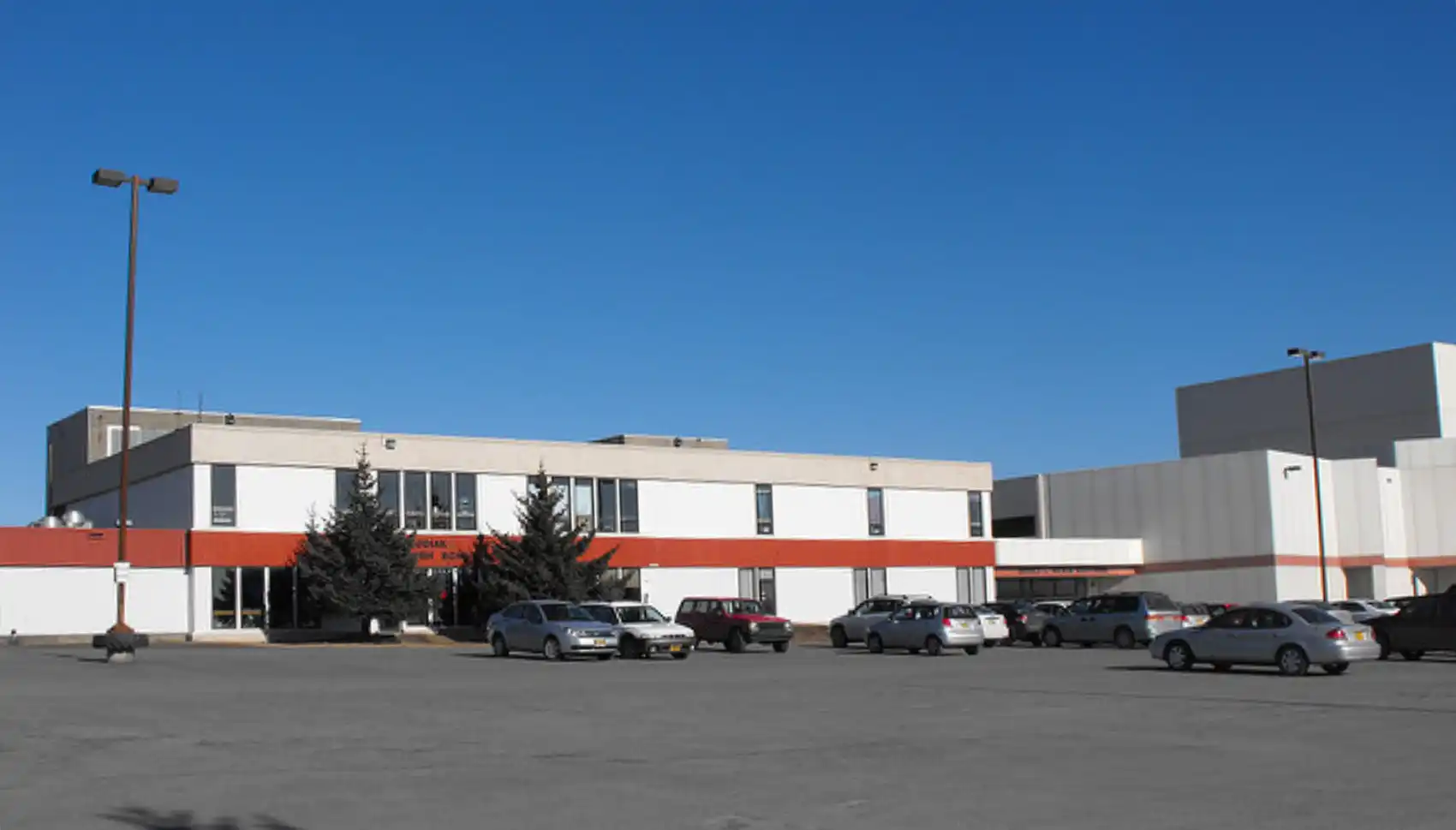 1970's blocky gray, white, and rust colored old school and asphalt parking lot.
