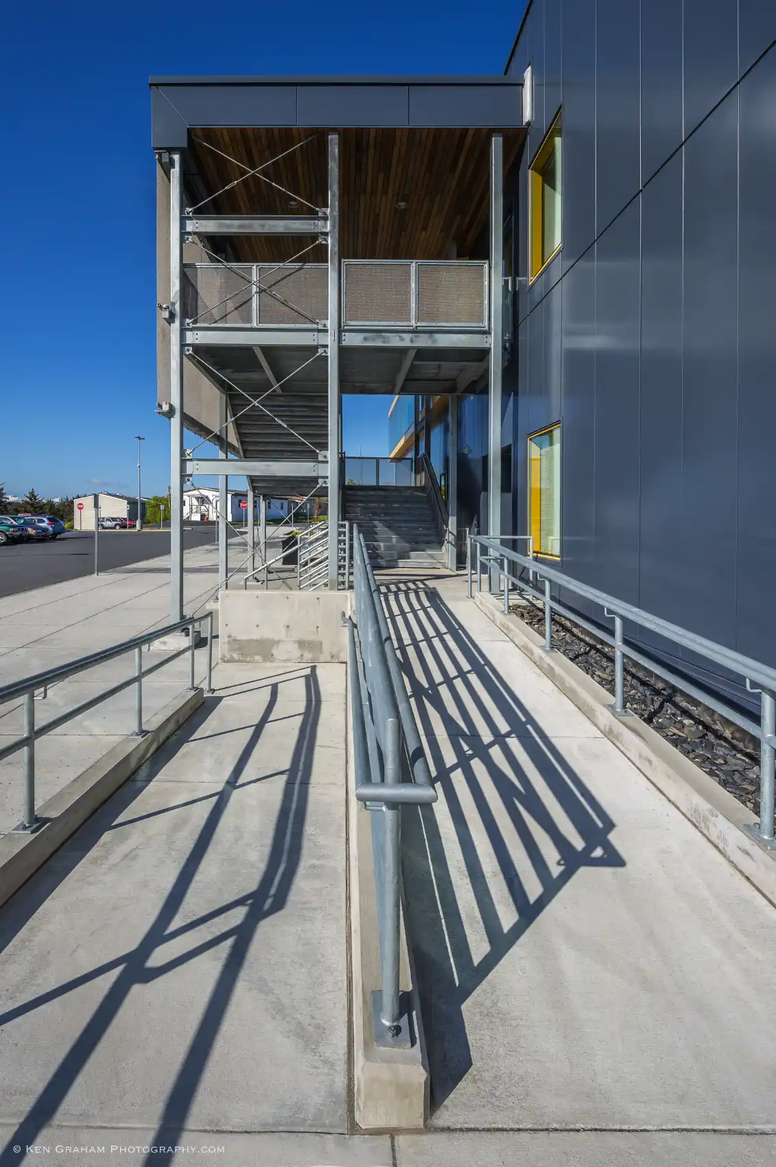 Emergency exit stairs with gray metal paneling, galvanized structure and railings, and woven metal fabric guardrails.