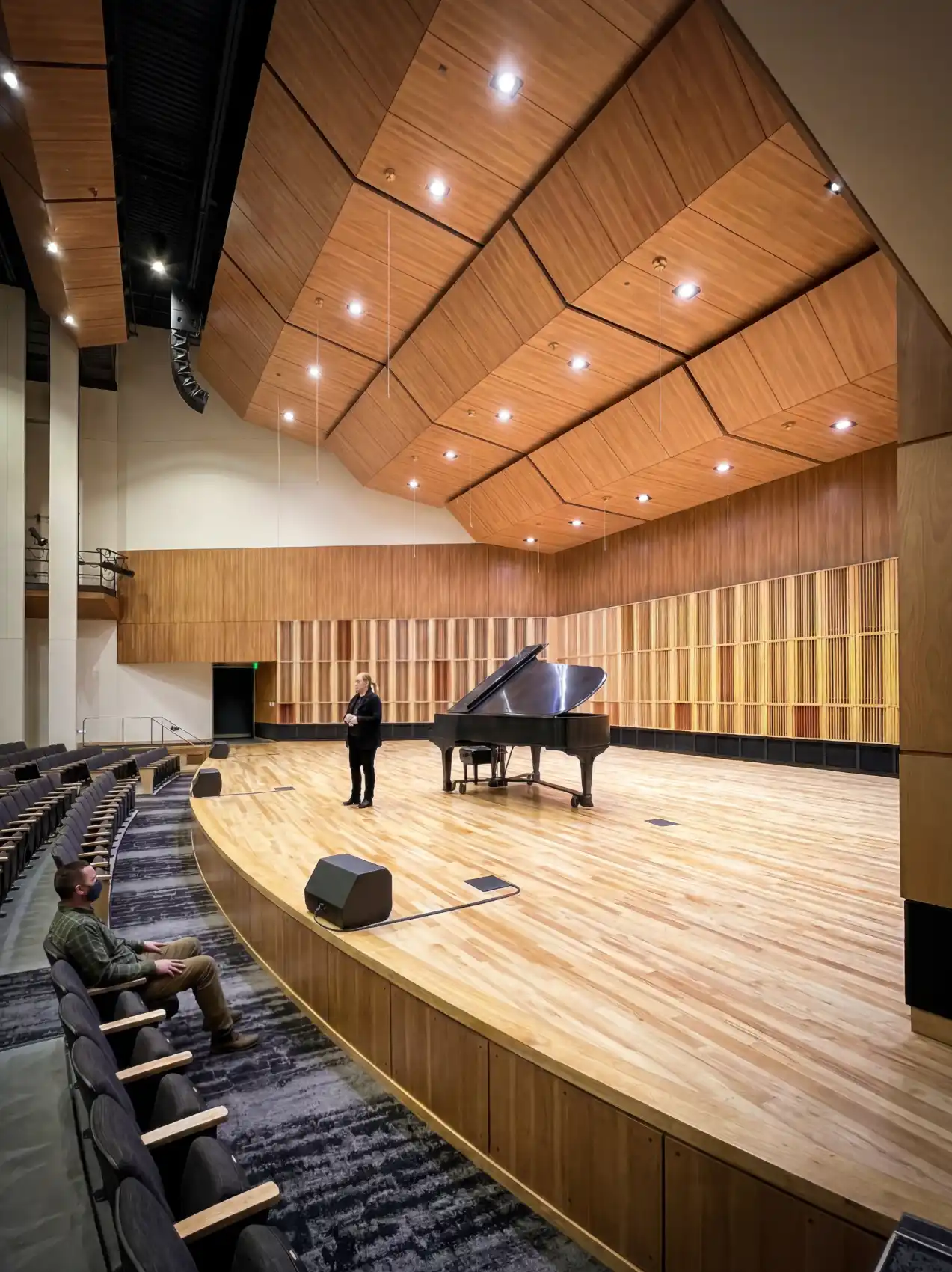View from the entry to the stage with a person standing next to a grand piano.