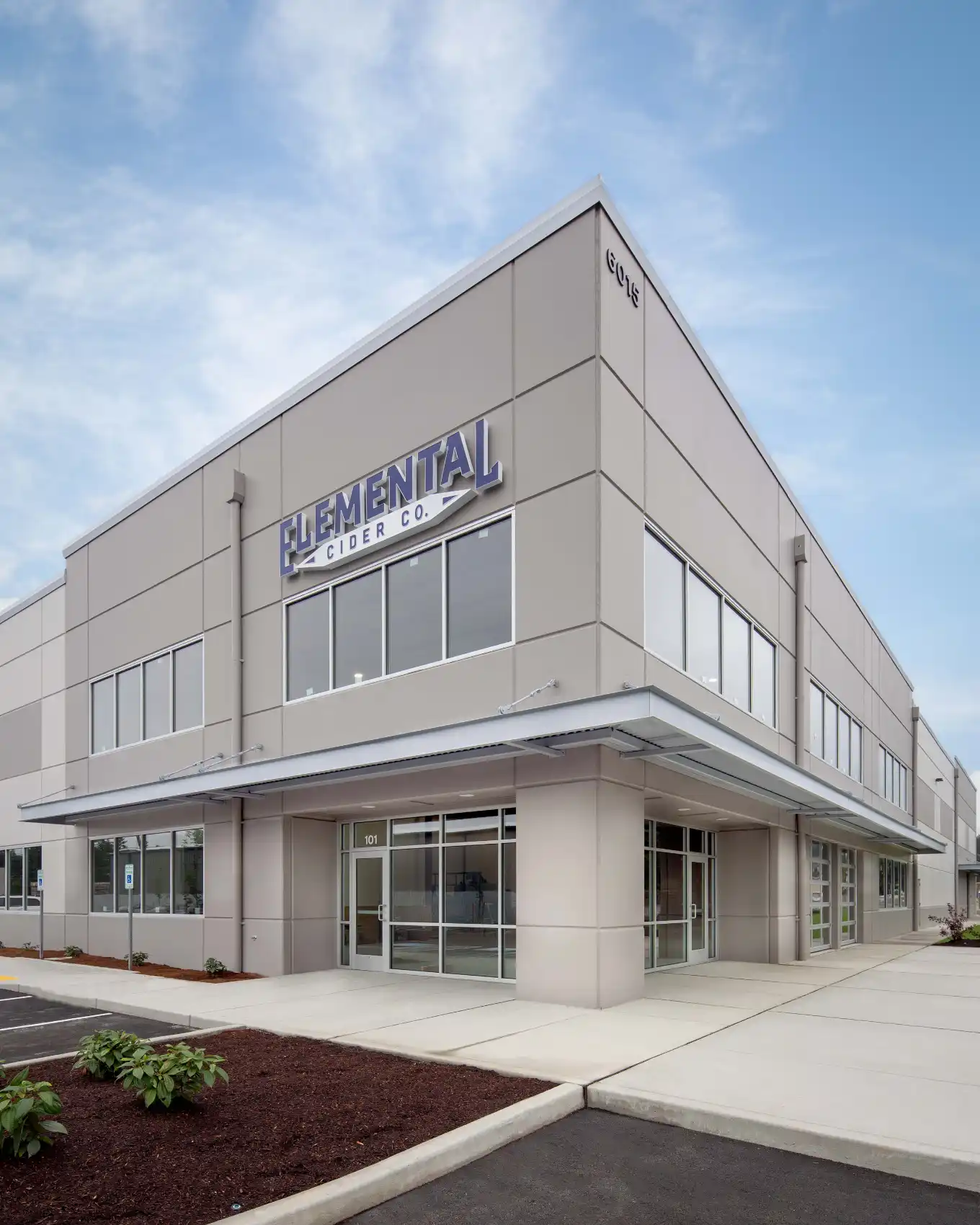 Corner of a 2-story concrete building with windows and a wrap around covered entry.