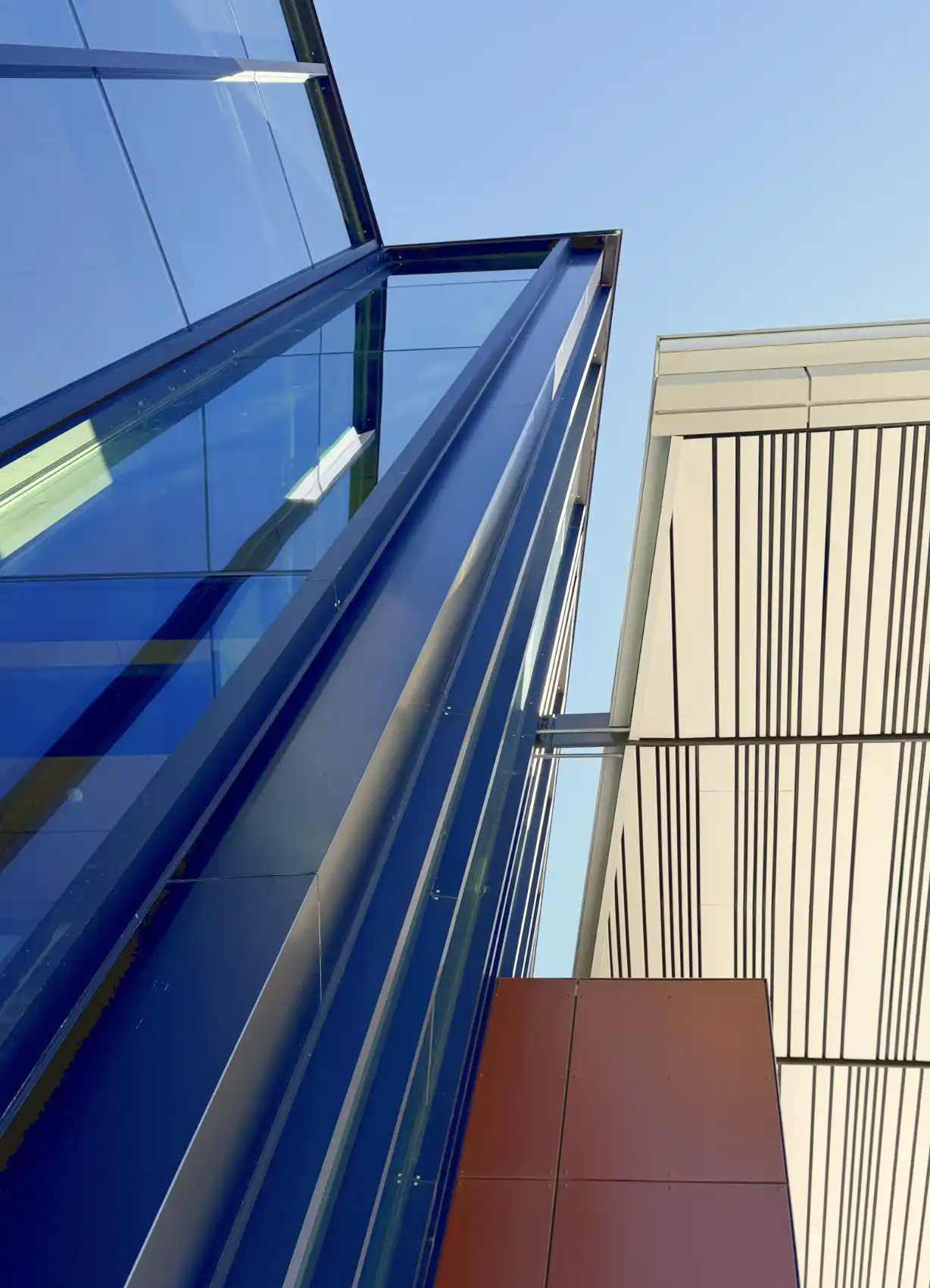Looking up at intersecting angles and lines of the glass curtain wall and covered entry.