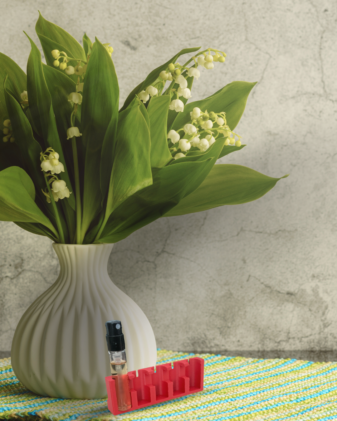 Personne portant une veste tricotée bleue et un pantalon marron ayant à la main un carnet rouge et une touche, les deux intitulés Nosebook, marchant près de l'eau.