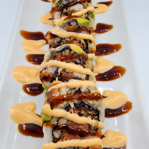 A sushi roll with sauce on it.