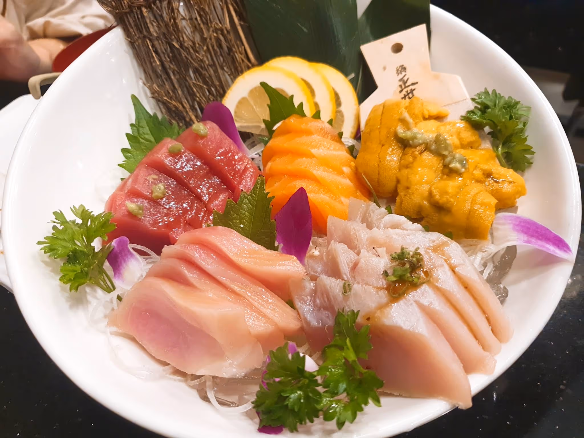 A plate of sushi with a lemon wedge and a yellow sauce.