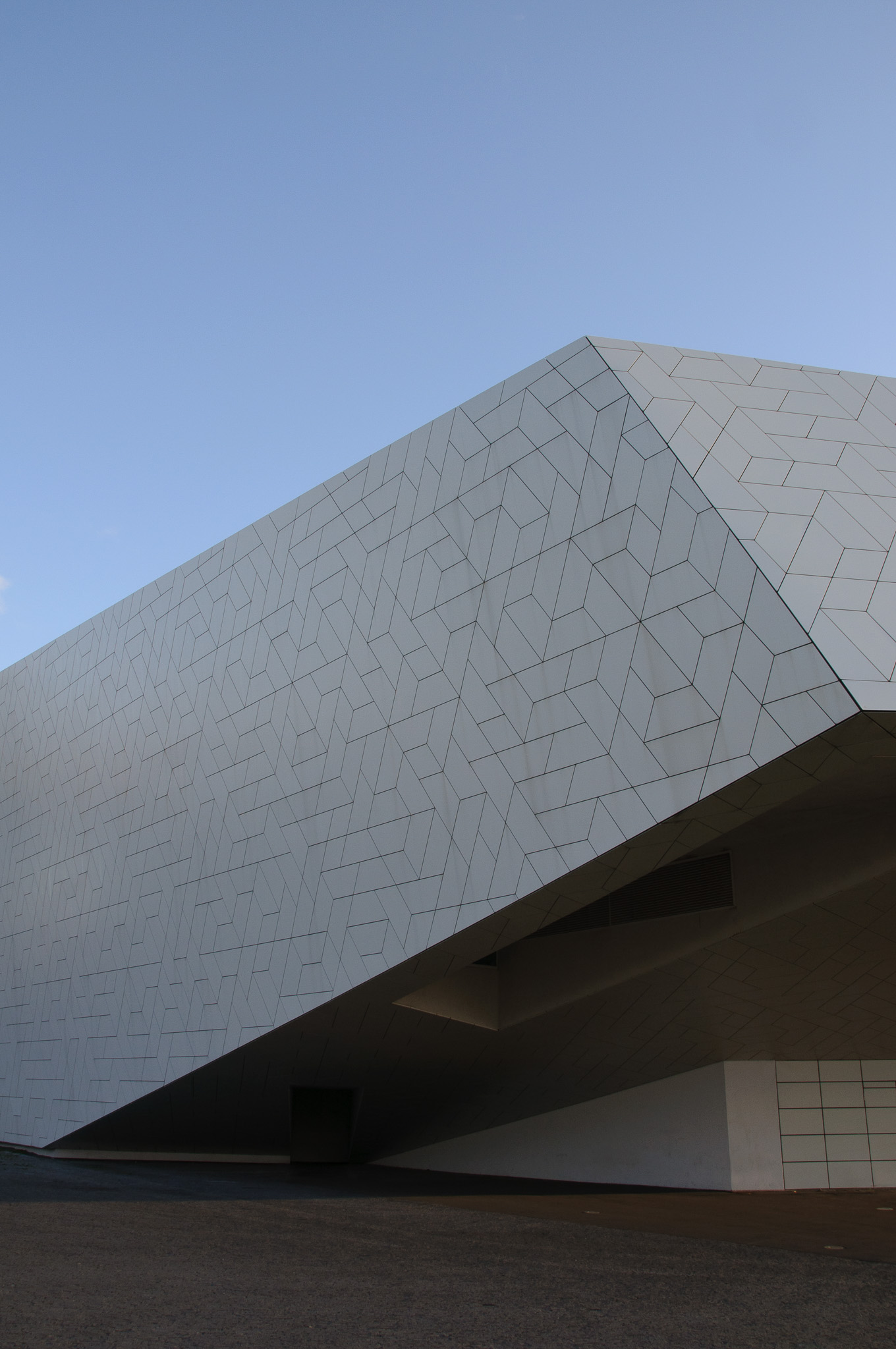 Modern building with white geometric patterned facade against a clear blue sky.