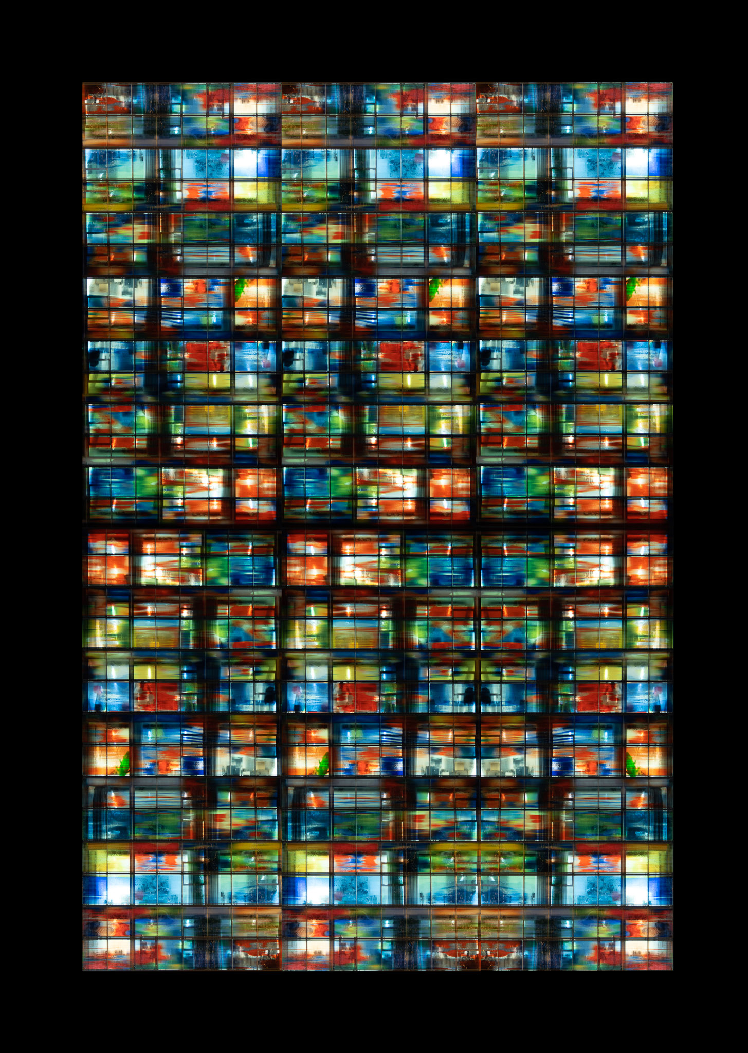 A colorful mosaic grid of illuminated abstract stained glass panels with red, blue, green, and yellow tones.