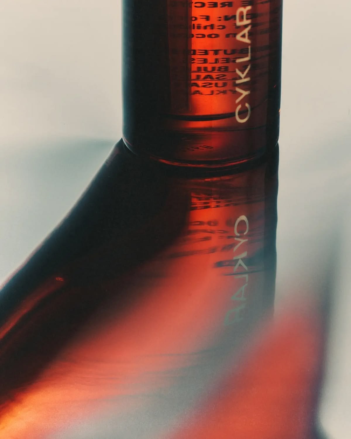 Amber glass bottle casting a long shadow across a pale surface