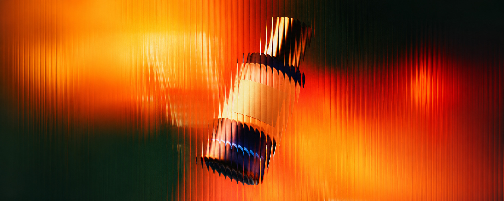 Backlit bottle behind amber and orange fluted glass