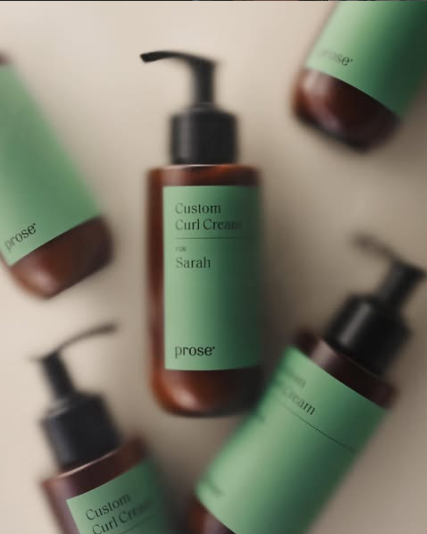 Custom-labelled hair care bottles with mint green labels and black pump caps arranged on a beige surface
