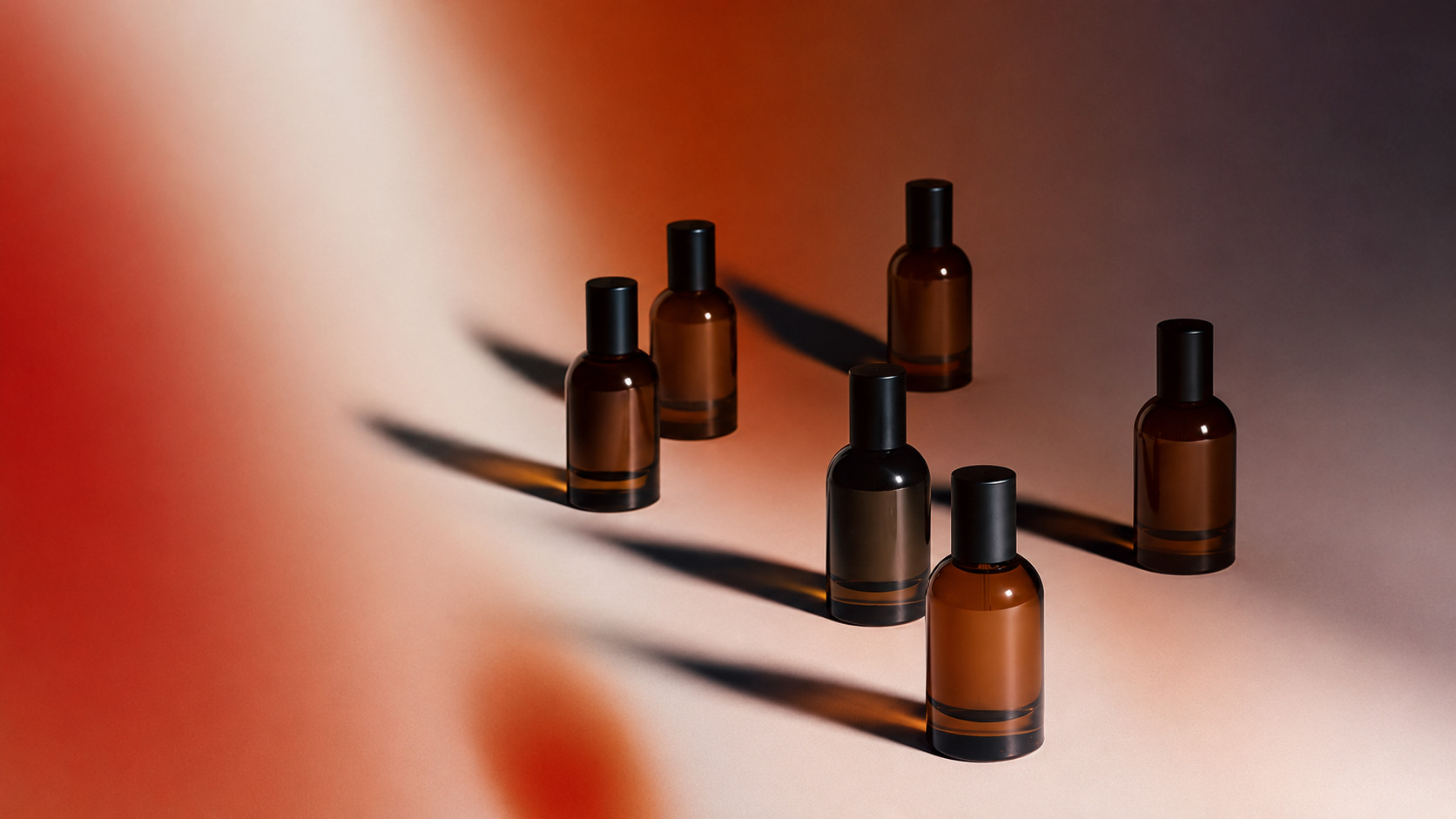 Two amber glass pump bottles casting long shadows on a warm terracotta backdrop