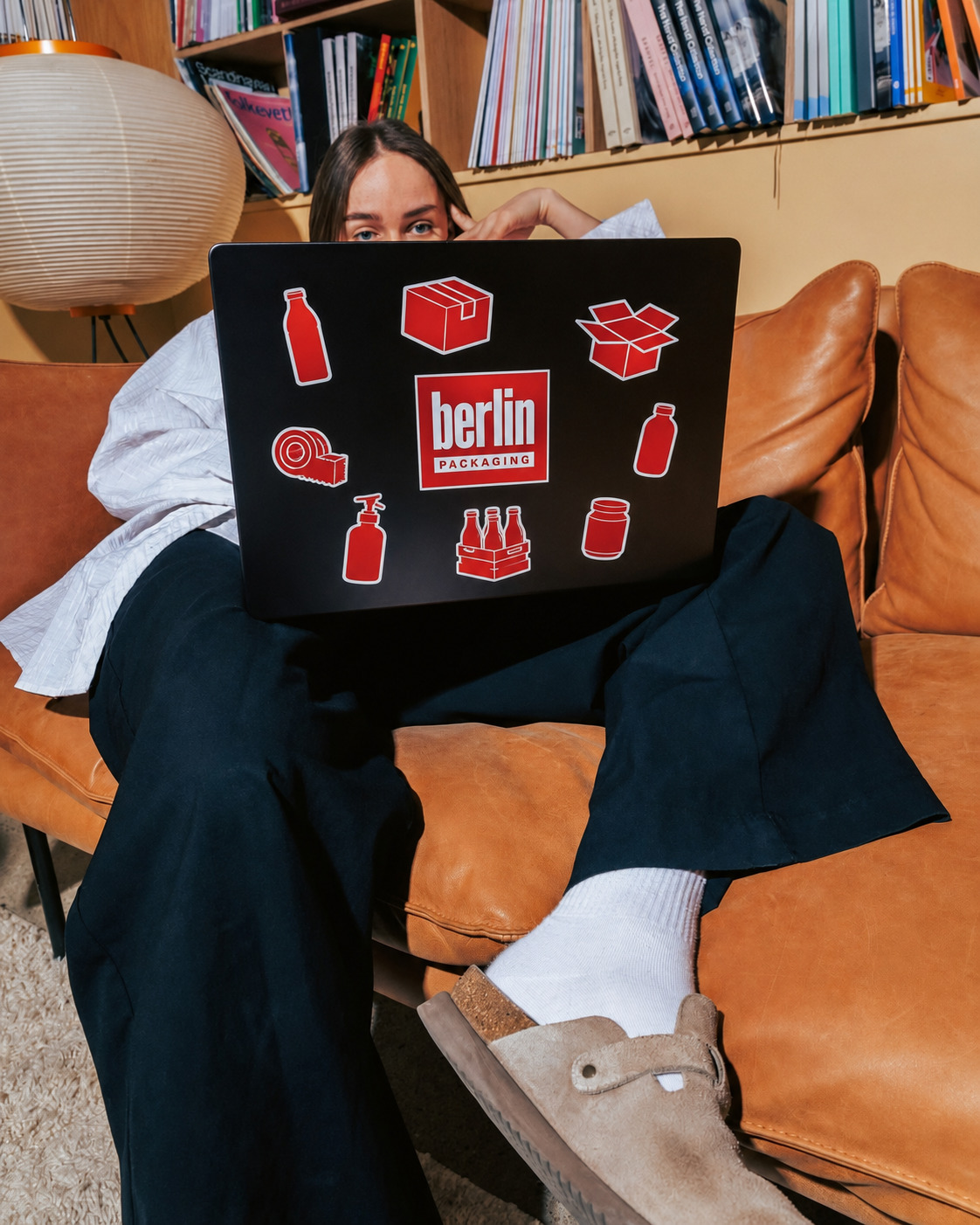 A customer working on a laptop covered in Berlin Packaging stickers
