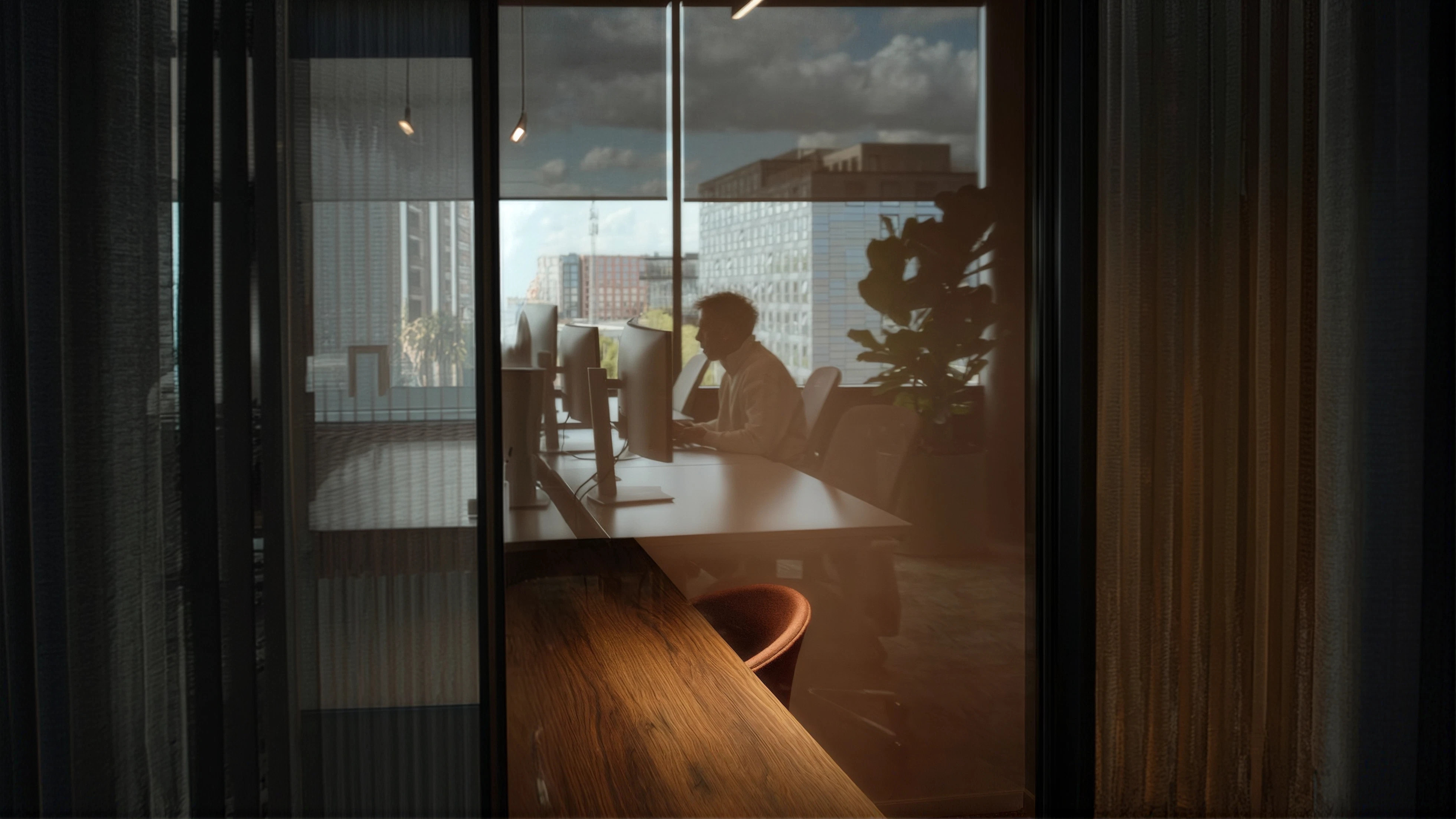 Team member working at a desk beside floor-to-ceiling office windows