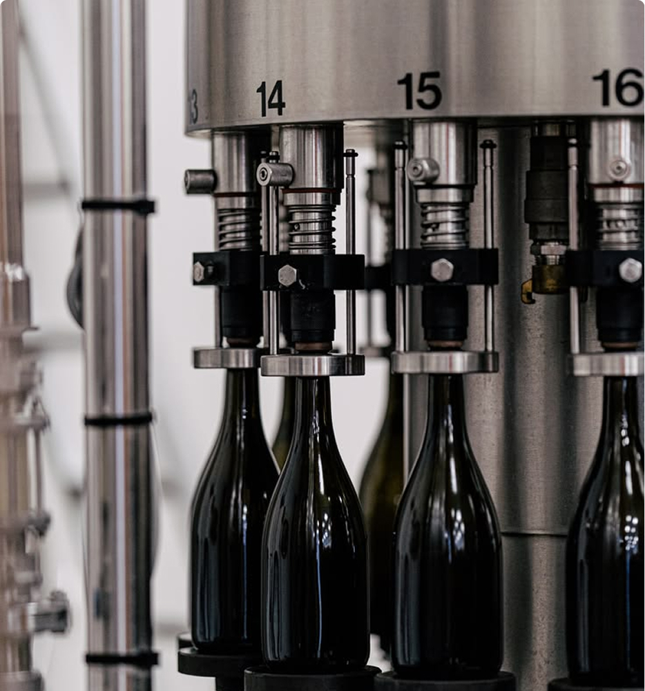 Numbered filling stations dosing dark glass bottles on a bottling line