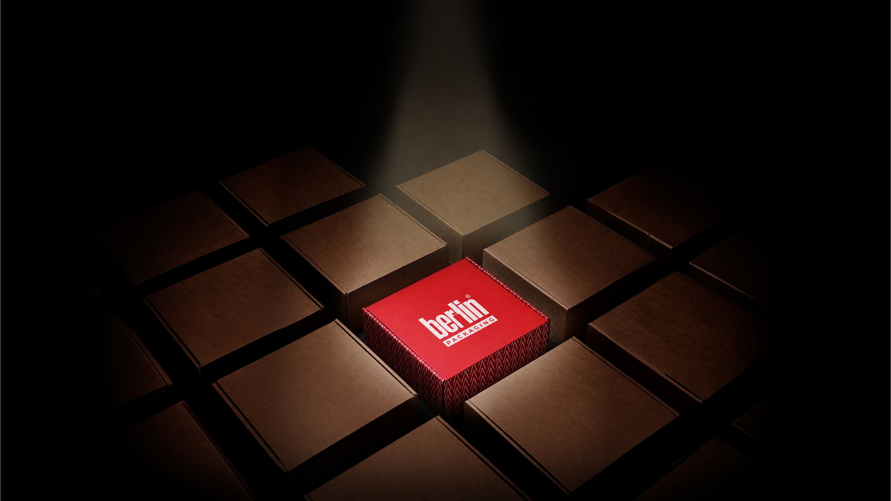 Red Berlin Packaging box lit among stacked kraft cartons