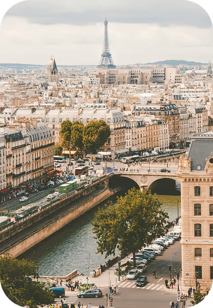 Vue aérienne de Paris avec la Seine, un pont, des bâtiments historiques et la tour Eiffel en arrière-plan sous un ciel nuageux.