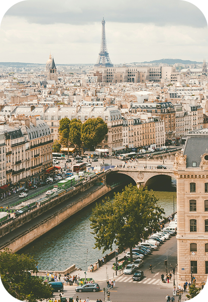 Vue aérienne de Paris avec la Seine, un pont, des bâtiments historiques et la tour Eiffel en arrière-plan sous un ciel nuageux.